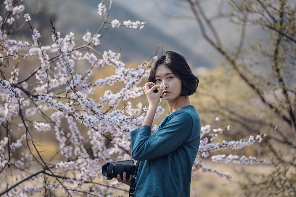 woman smelling cherry blossoms flower during daytime
