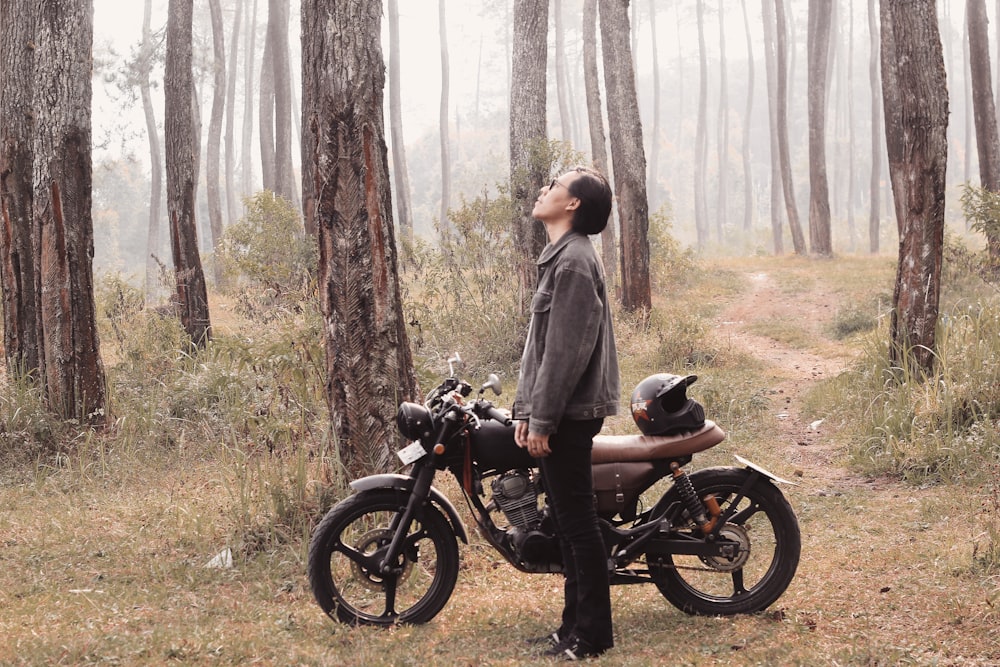 a man standing next to a motorcycle in a forest