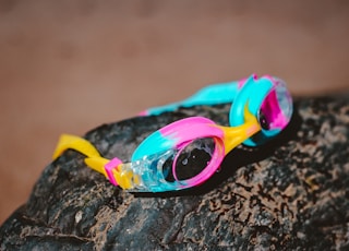 teal and pink goggles on brown boulder