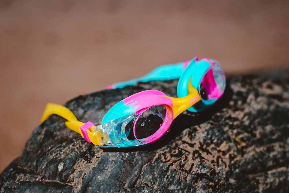 teal and pink goggles on brown boulder