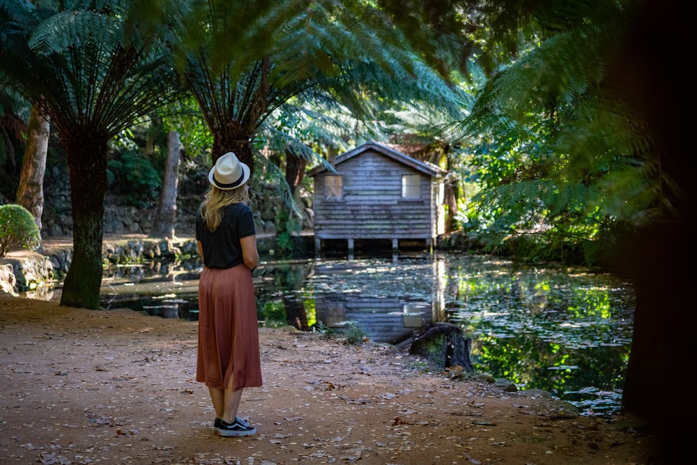 person wearing gray fedora hat standing near body of water