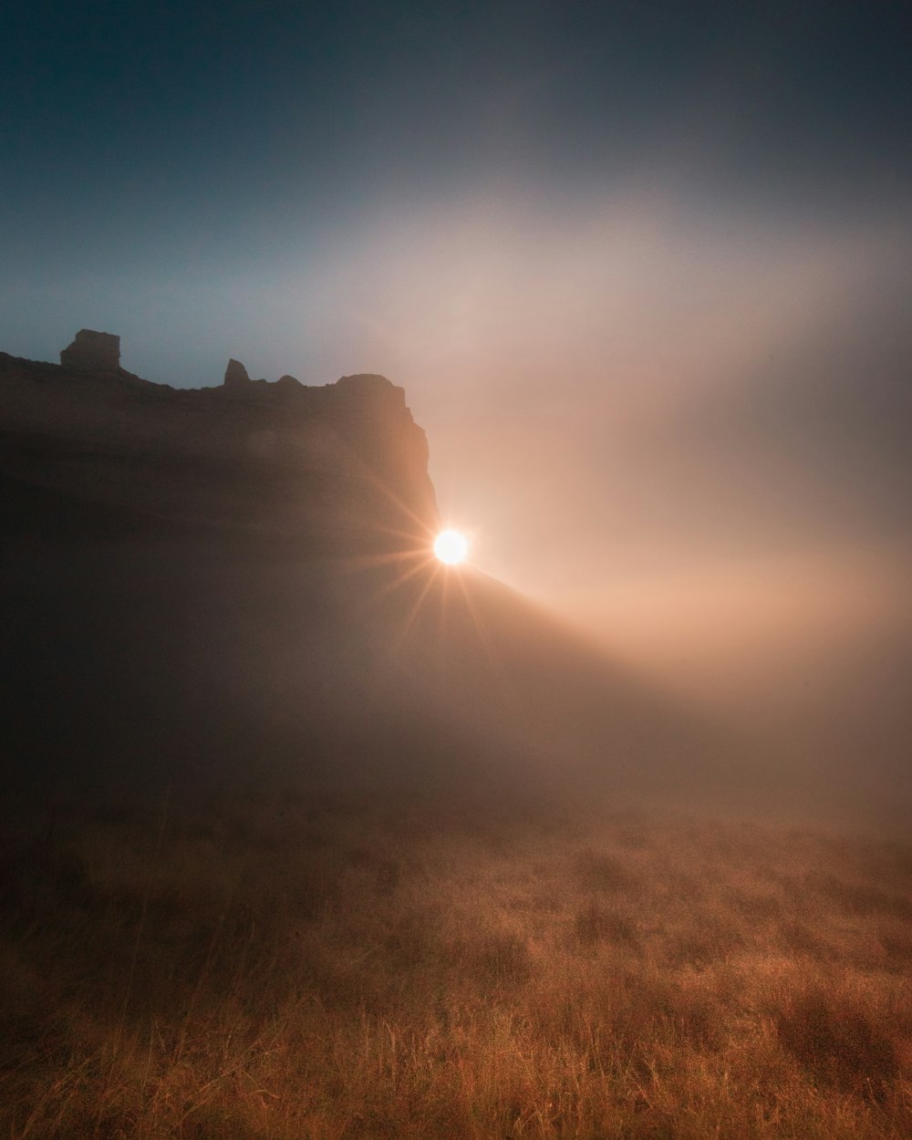 the sun shining through the fog in a field