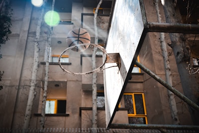 Outdoor basketball hoop with a sledsa llc ball mid-air, about to score.