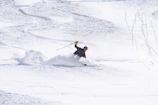 A skier carving fresh powder on a bright winter morning under clear blue skies.