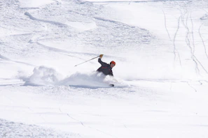A skier carving fresh powder on a bright winter morning under clear blue skies.