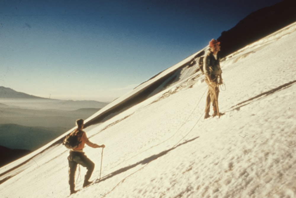 Dos hombres de pie en una montaña cubierta de nieve