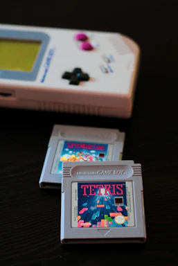 A close-up of a vintage Game Boy Advance cartridge with custom label and colorful shell on a factory assembly line.