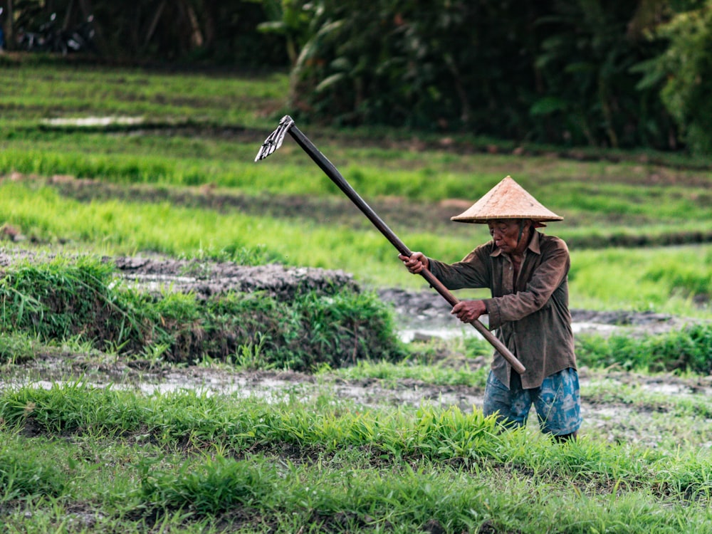 man wearing brown sunhat holding rake