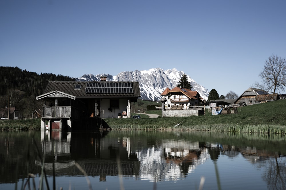 white and brown wooden houses near lake and mountain