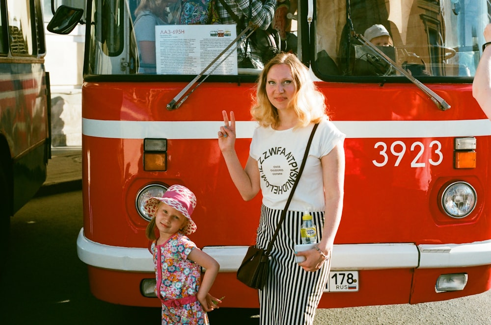 girl and a woman standing in front og the red bus