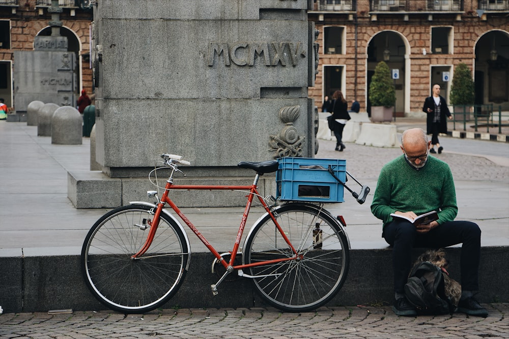 red bicycle beside man sitting on park