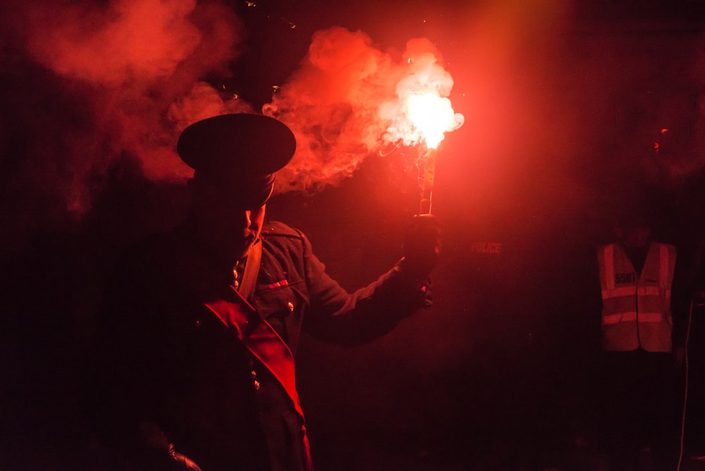 Persona sosteniendo un palo de humo rojo