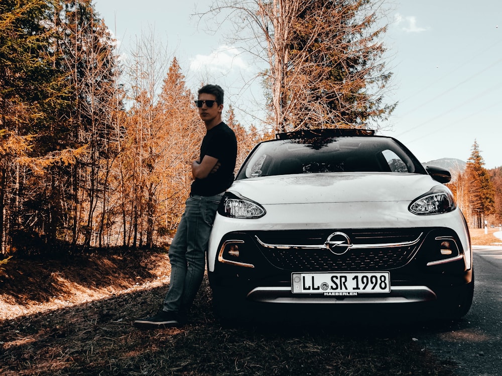 hombre apoyado en un coche Opel blanco