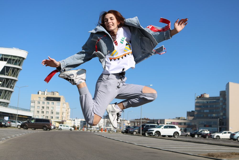 woman wearing blue denim jacket and distressed blue denim jeans jumping during daytime