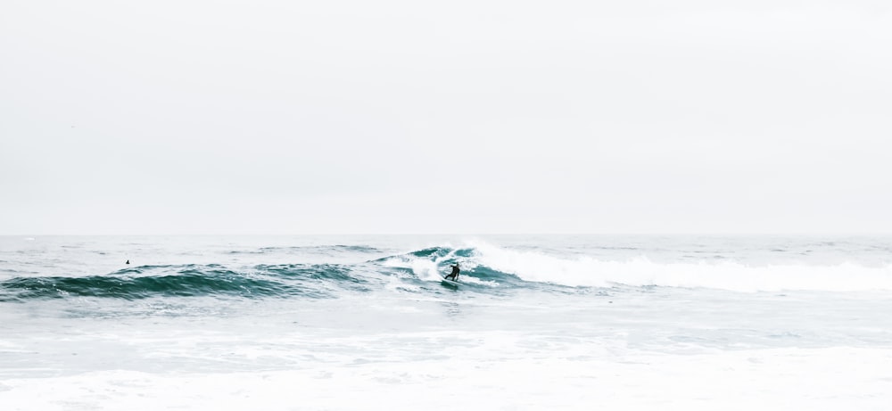 a man riding a wave on top of a surfboard