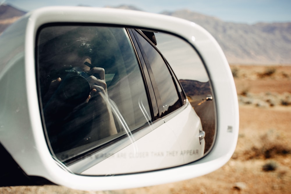 view of vehicle behind white vehicle reflected on side mirror