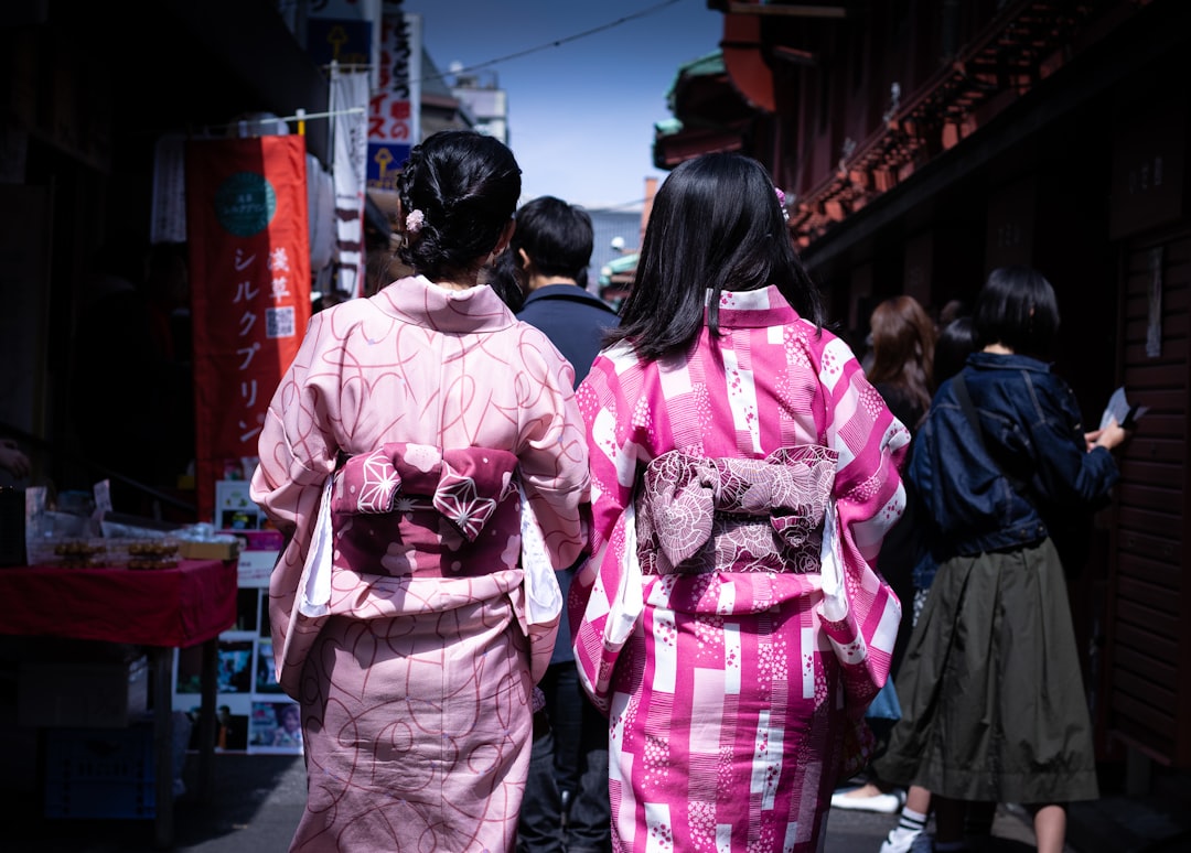 two women wearing pink apparels walking between buildings