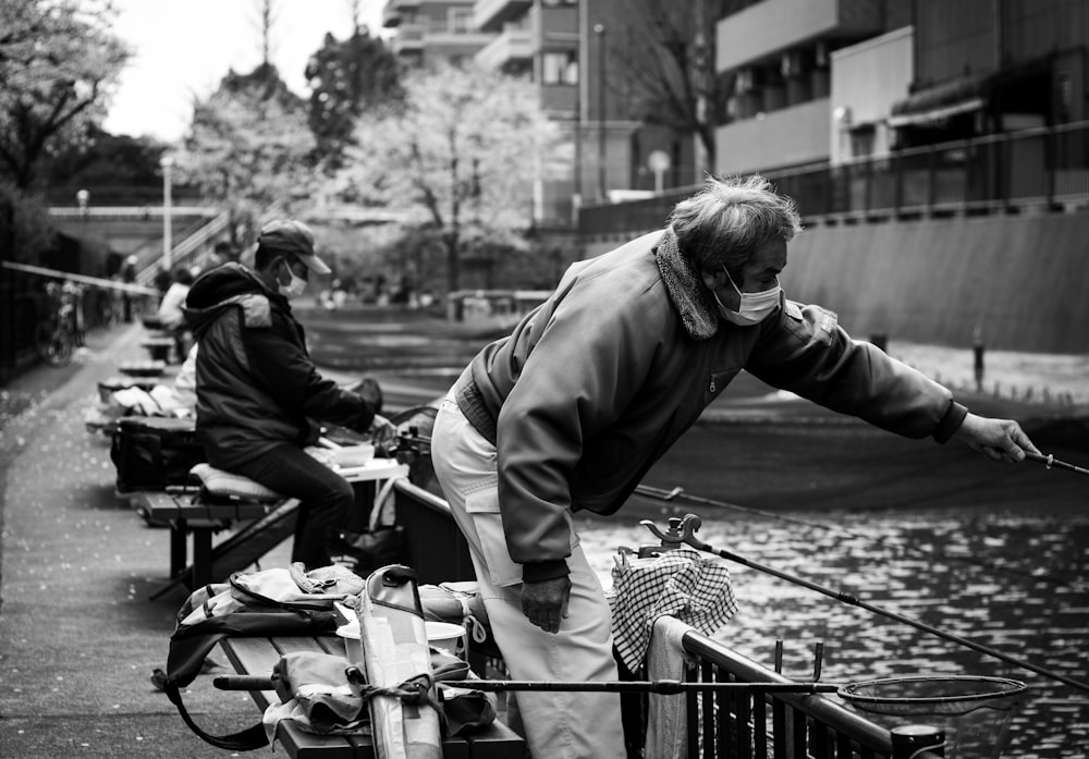 grayscale photo of man fishing on river