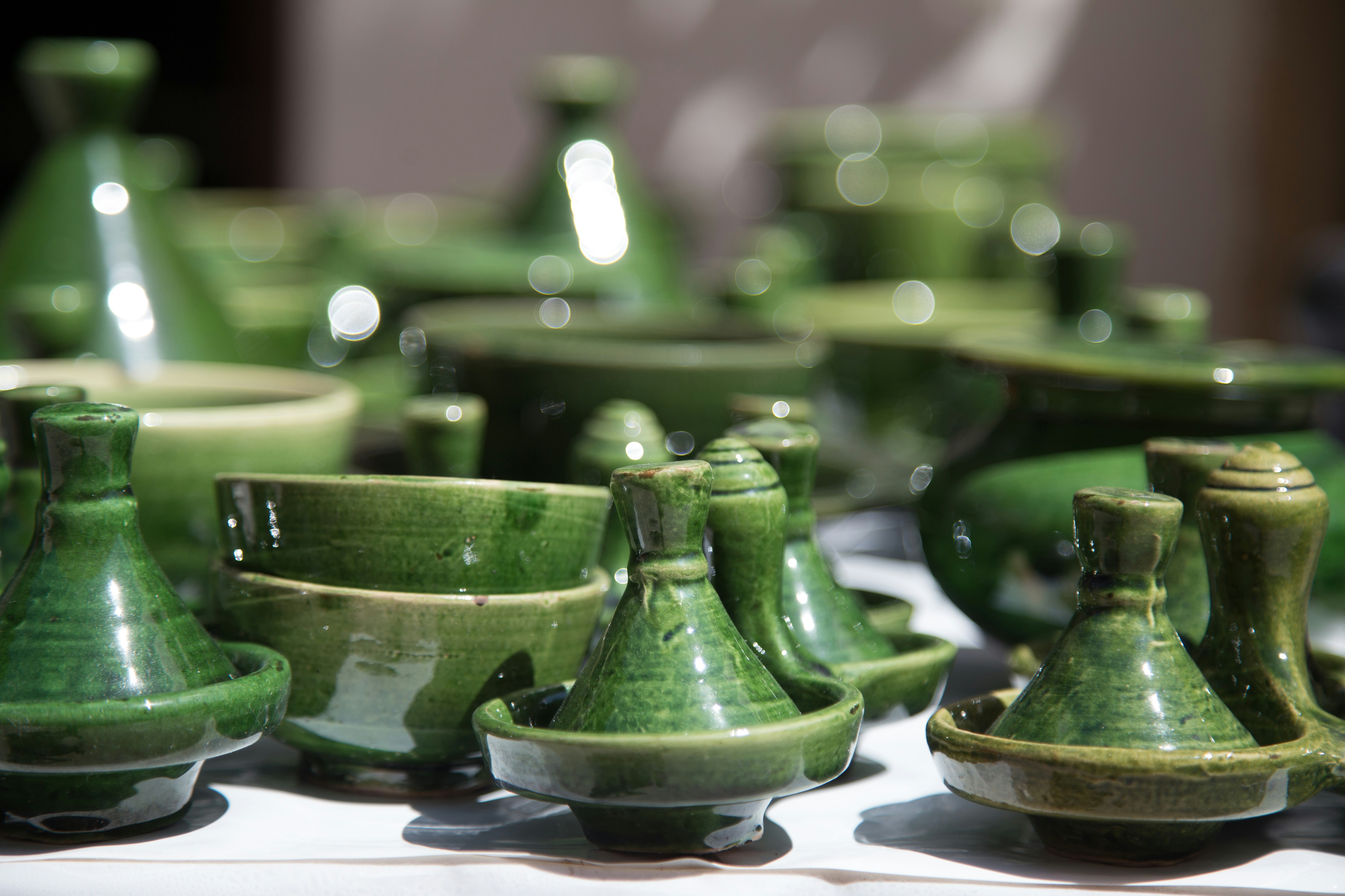 Collection of artisan ceramic pots in sage green and terracotta arranged on natural wood surface