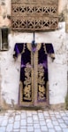 purple and gold long-sleeved dashiki dress hanging by a window