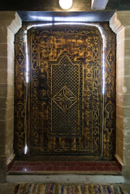Close-up of intricate cantera stonework framing a traditional wooden door in warm golden light.