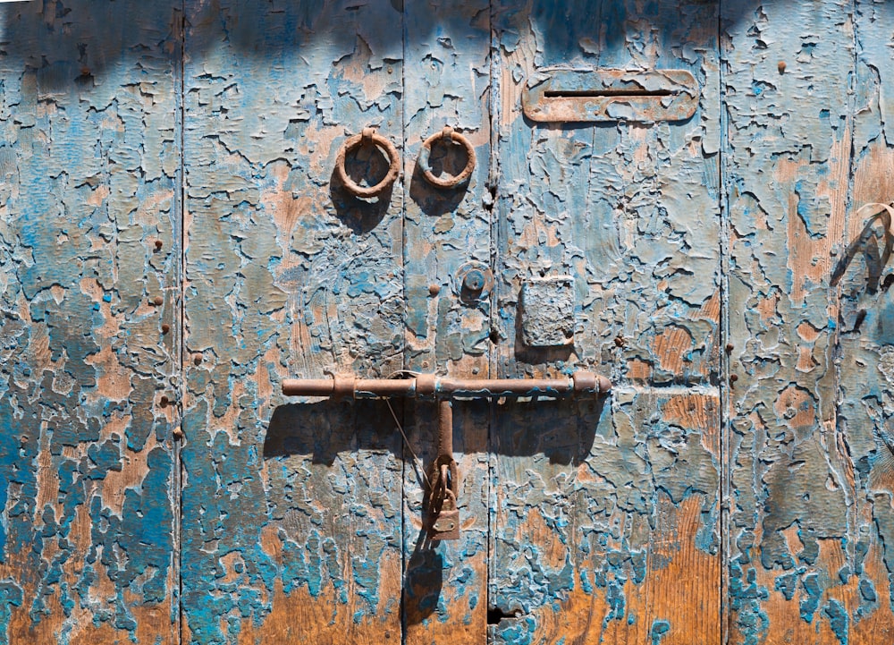 a rusted metal door with two knobs on it