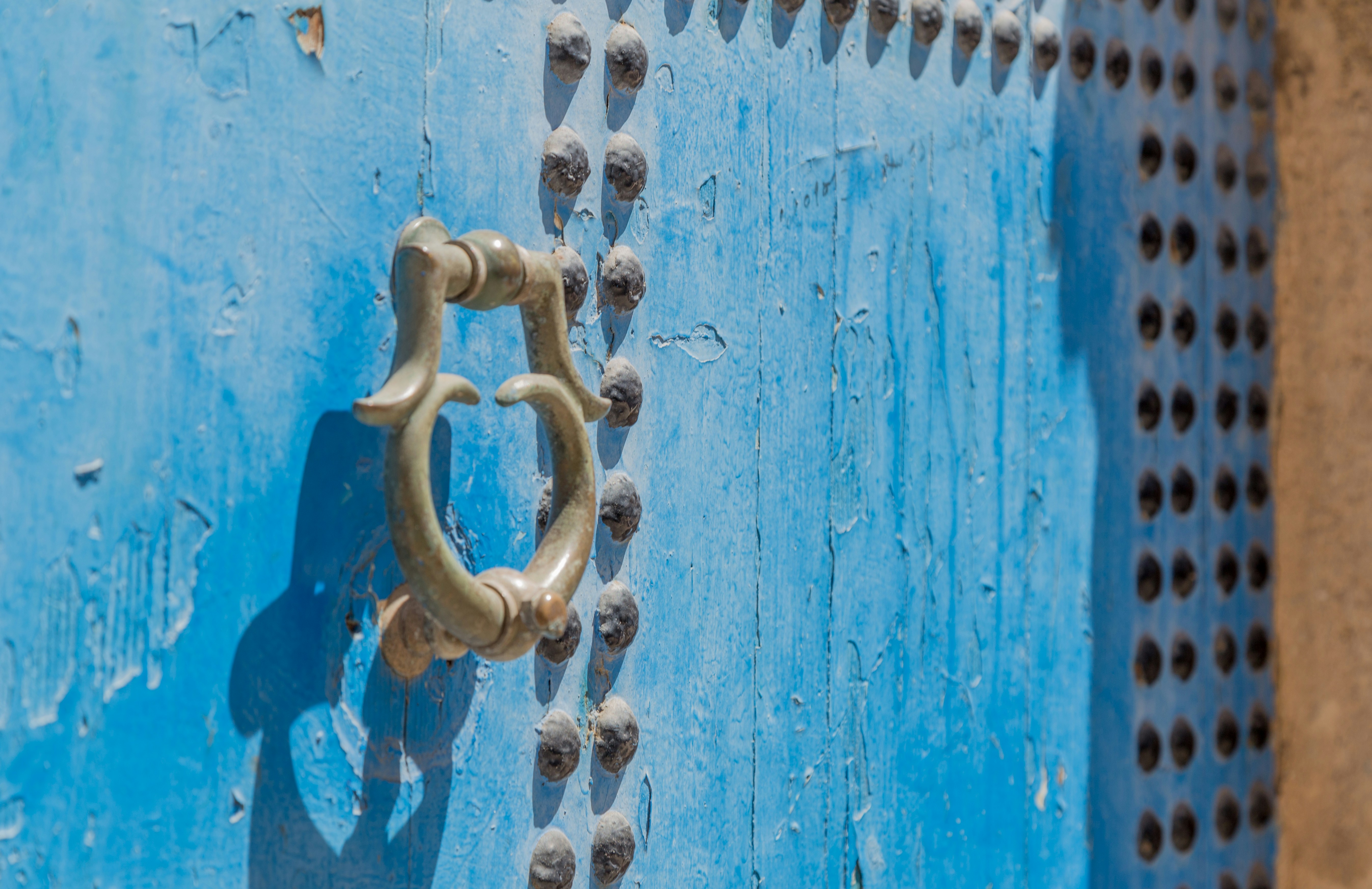 grey door knocker on blue wooden door with rivets, 