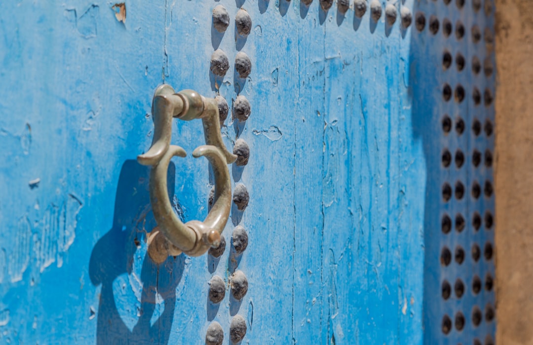 grey door knocker on blue wooden door with rivets,