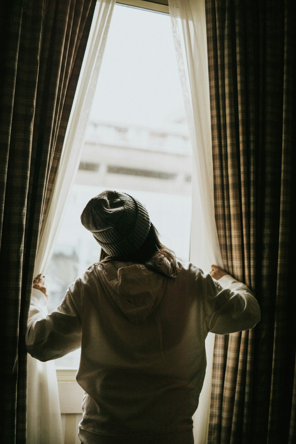 woman in white hoodie starring by the window