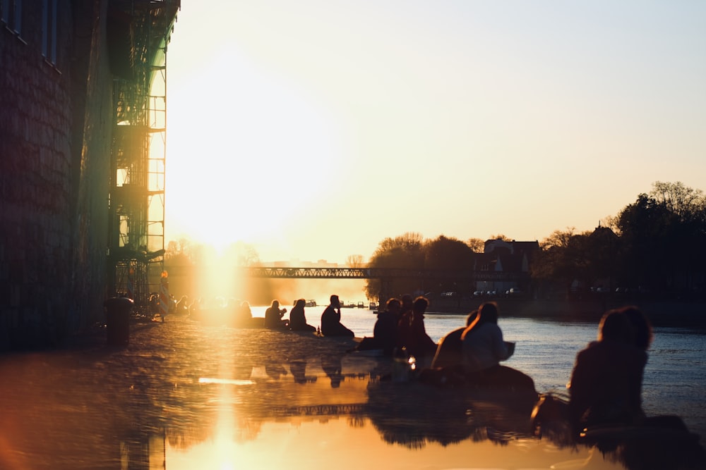 silhouette of person sitting beside body of water