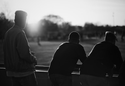 grayscale photography of three men standing near railings