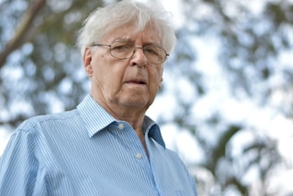 selective focus photography of man wearing blue and white striped collared top
