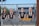 Four cutout images of people are mounted on a metal fence with a sports stadium in the background.