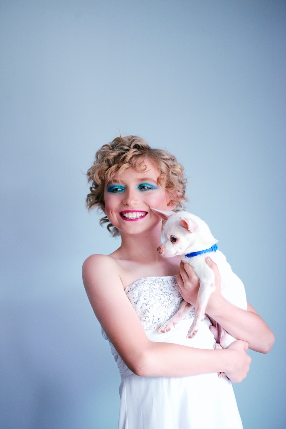 woman in white tube-top dress carrying white chihuahua