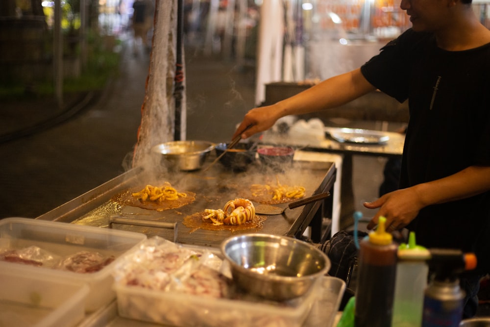 man in black t-shirt cooking on griddle