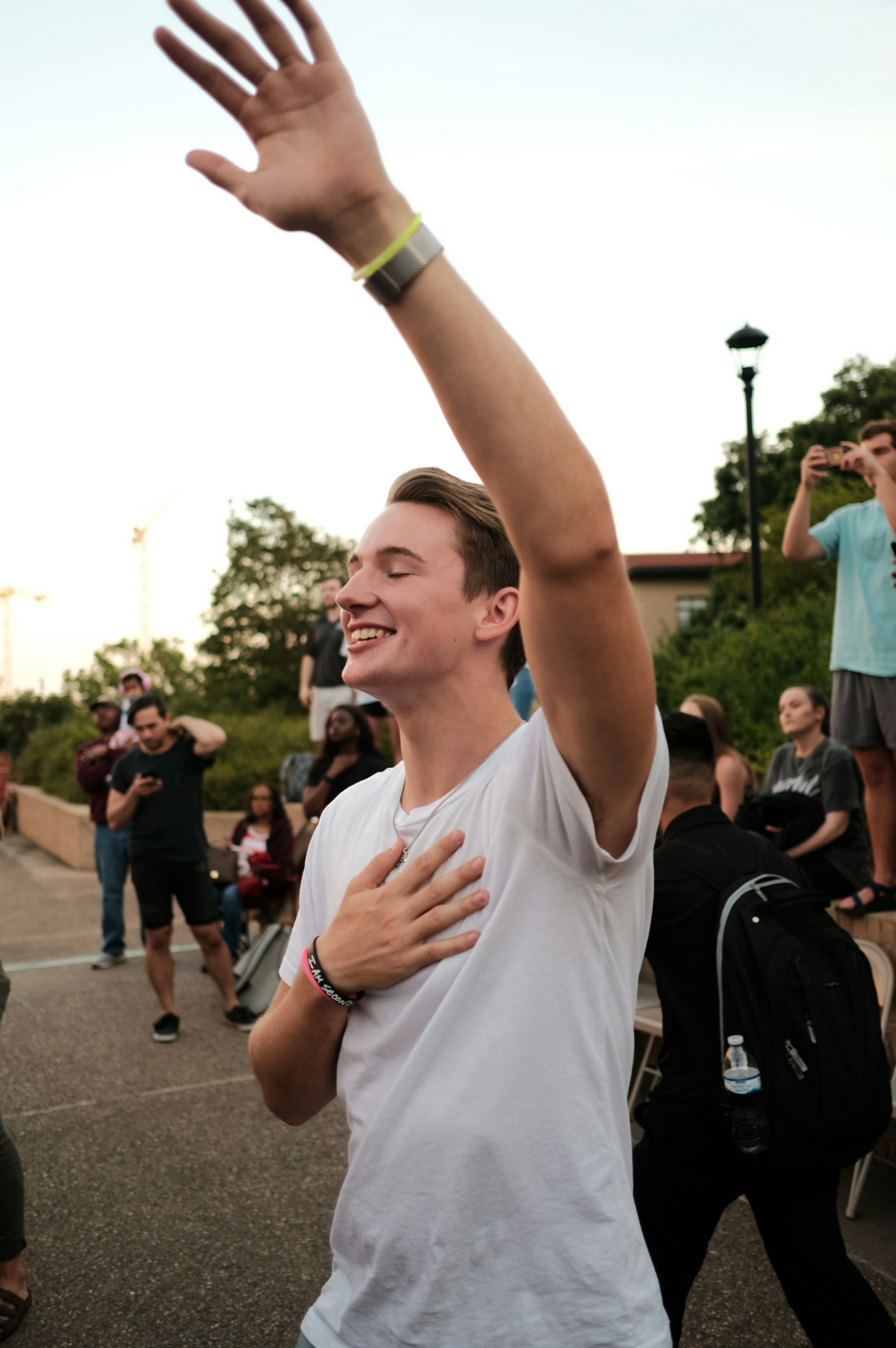 A joyful person raising hands in worship outdoors.