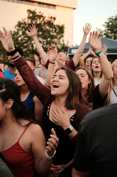 crowd of people standing while raising their hands