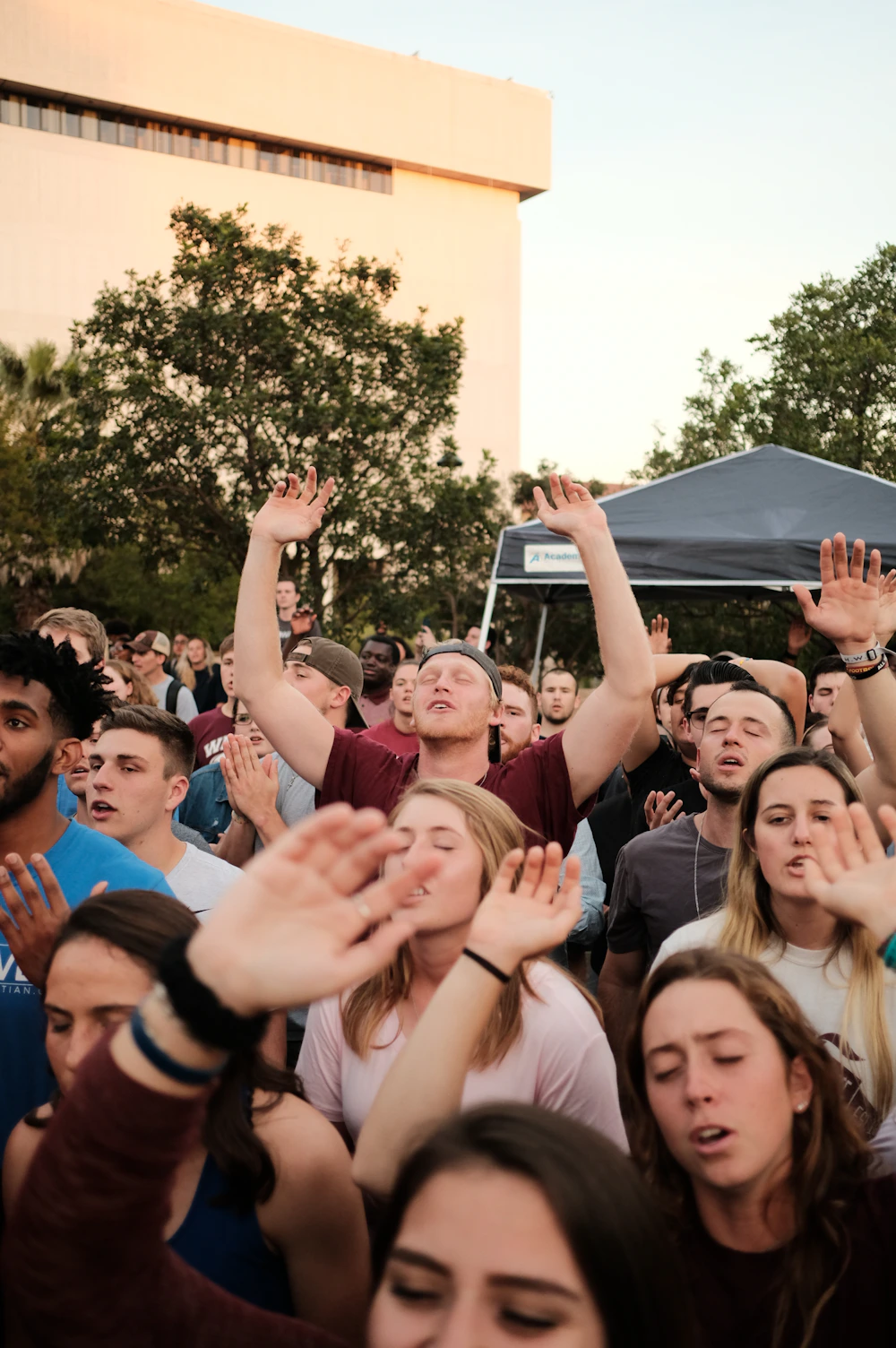 People standing with hands raised in prayer
