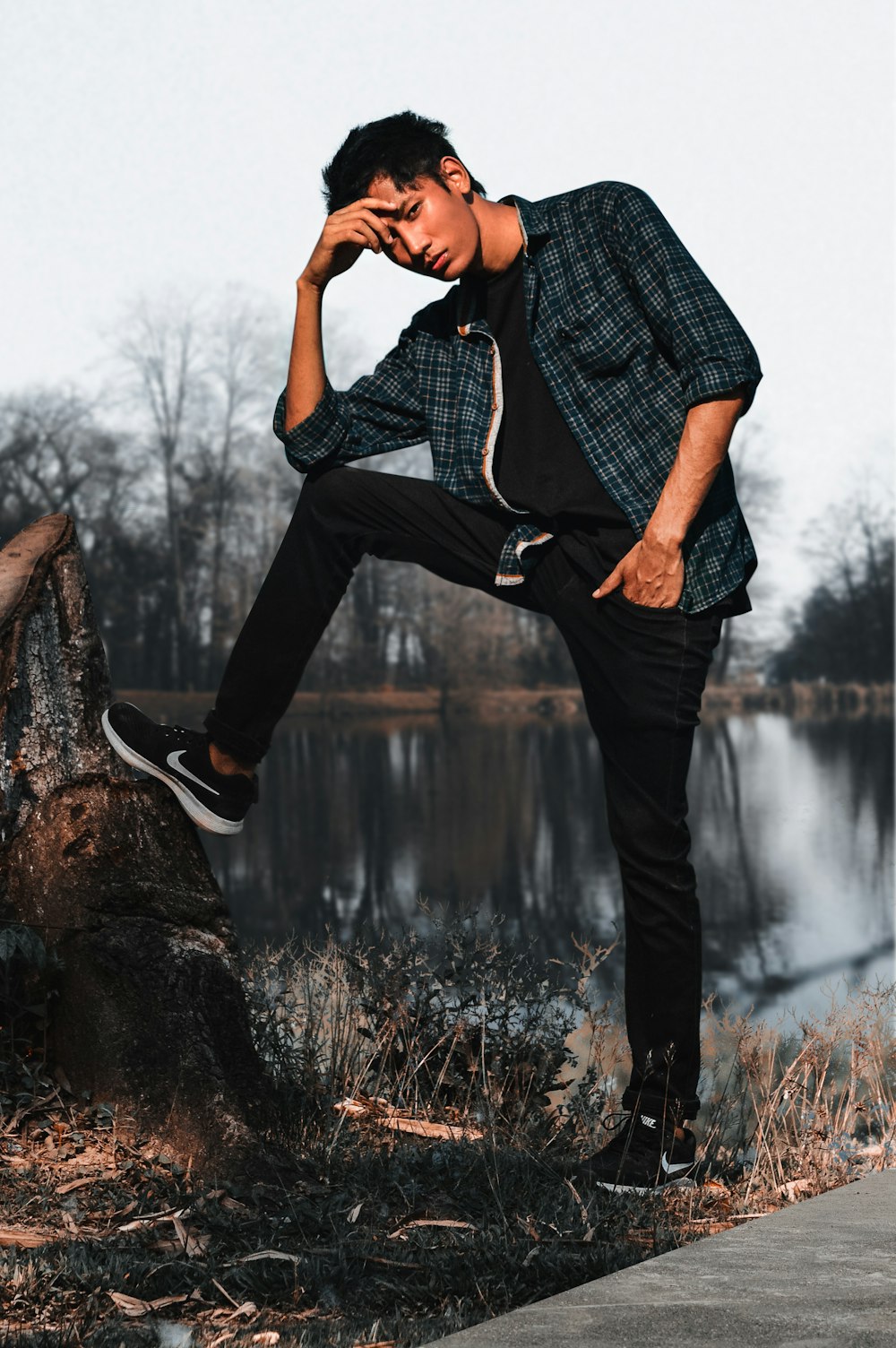 man resting his right foot on tree stump