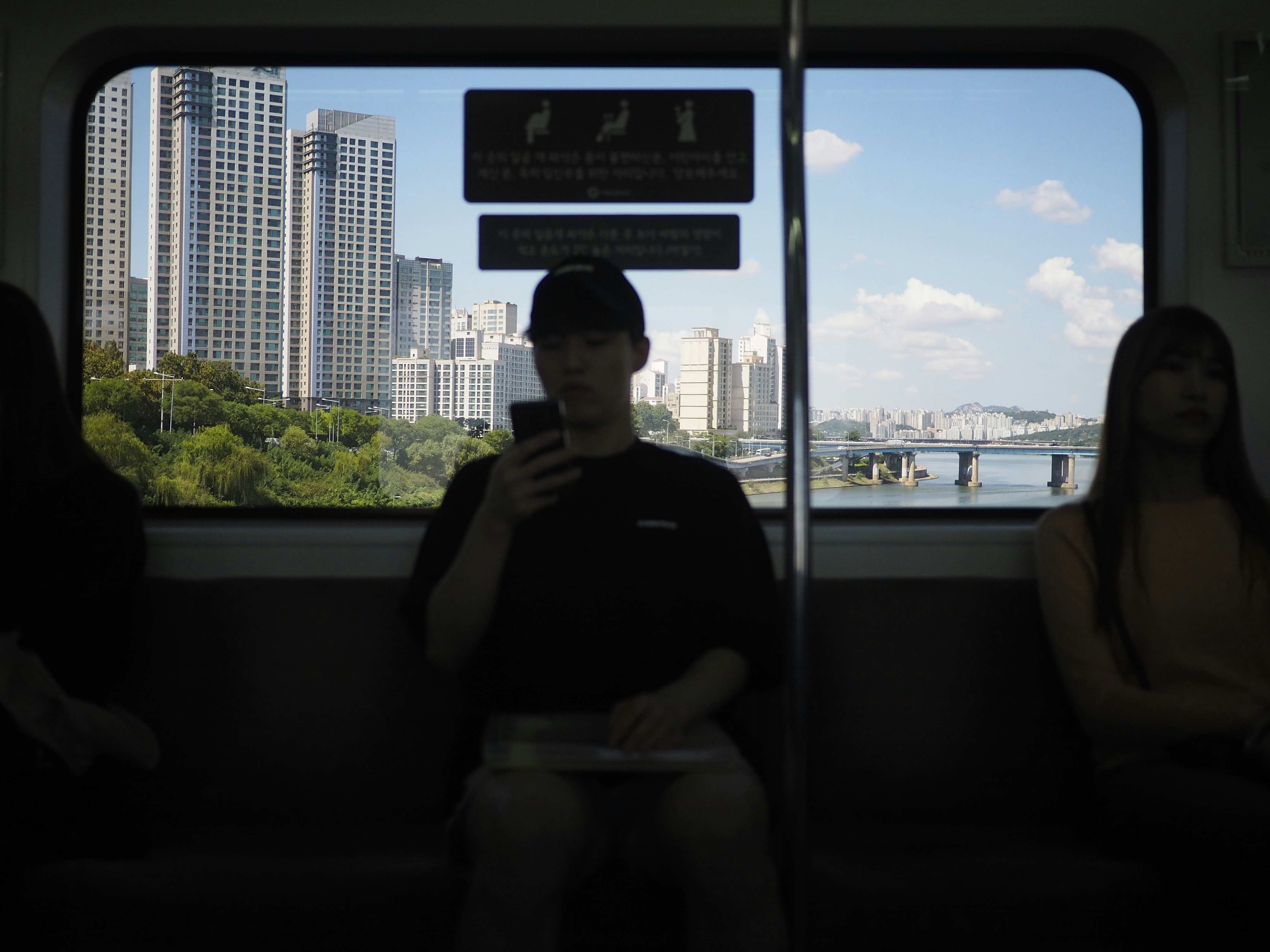 man sitting inside subway train holding smartphone