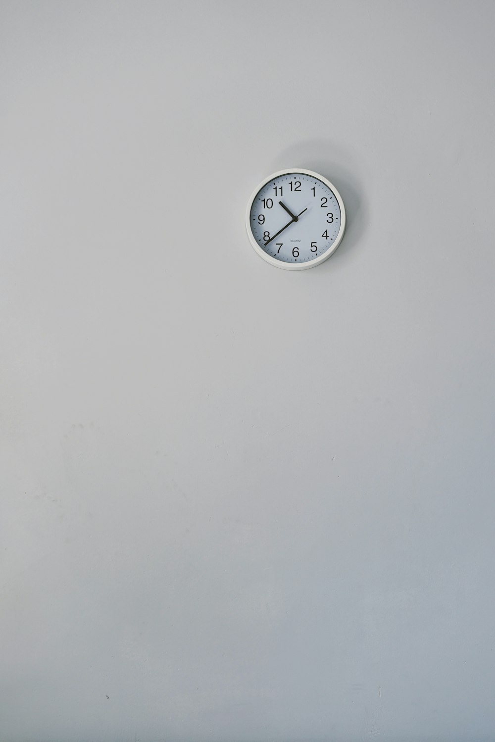 10:38を表示する丸い白いアナログ壁掛け時計