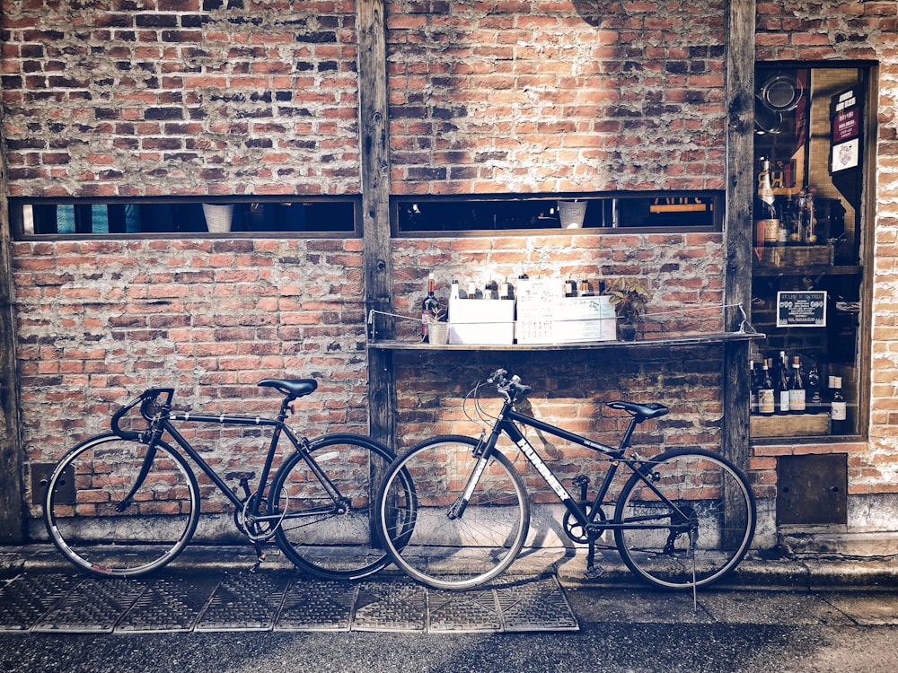 two black bikes in front red brick wall