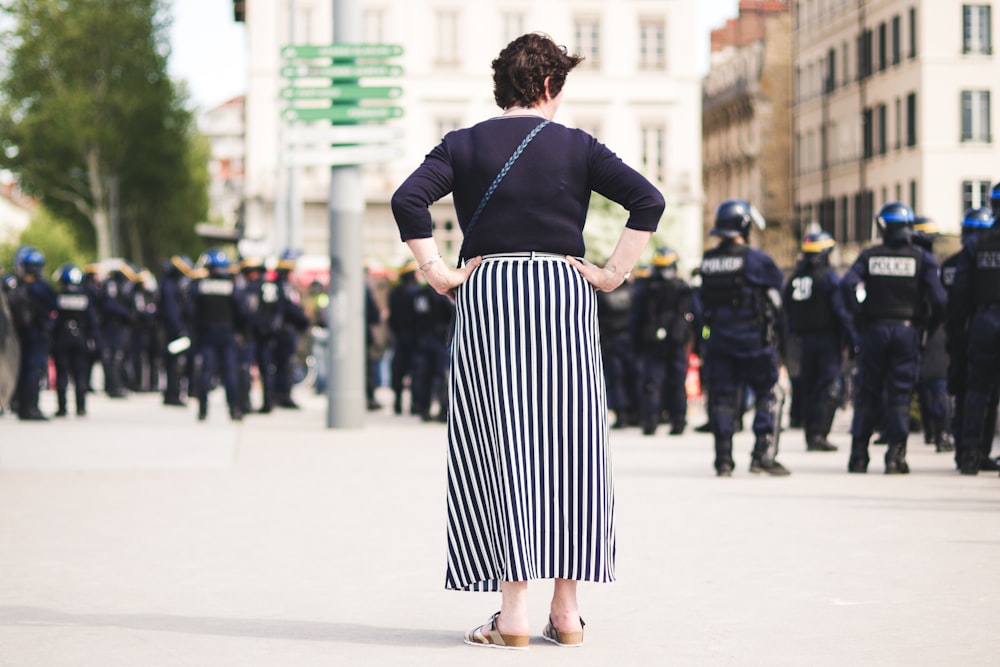 woman in black long-sleeved shirt standing alone behind people gathering