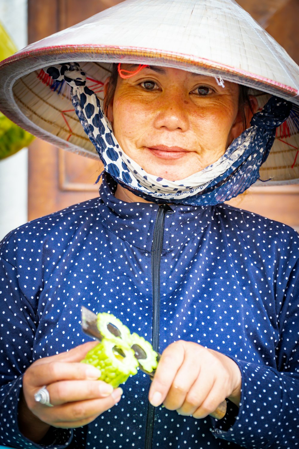 woman in white hat and blue top slicing vegetable