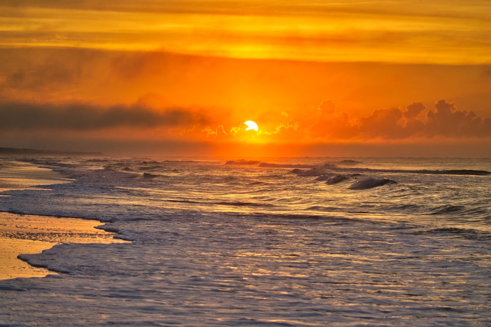 Onde del mare che si infrangono sulla riva sotto il tramonto