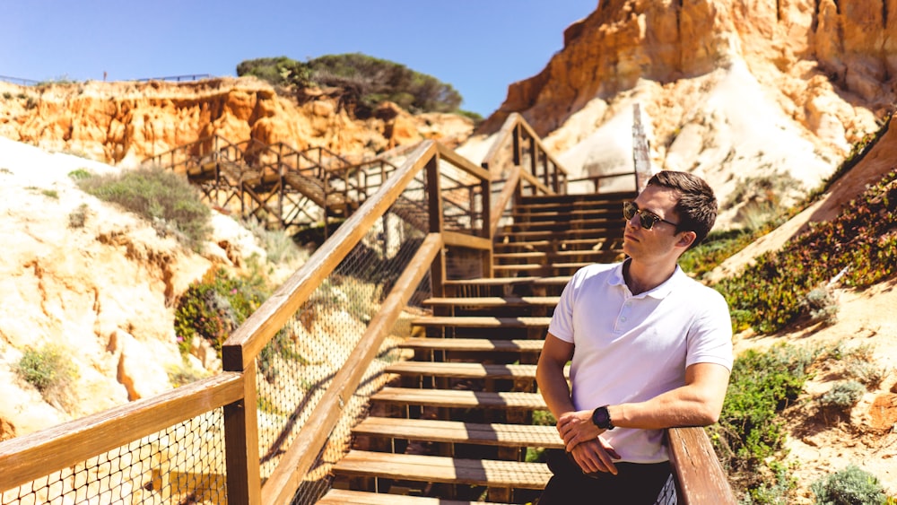 man standing beside wooden rail