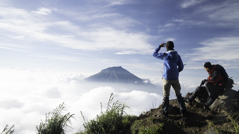 Dua pendaki mendaki tektok mencapai puncak gunung saat sunrise