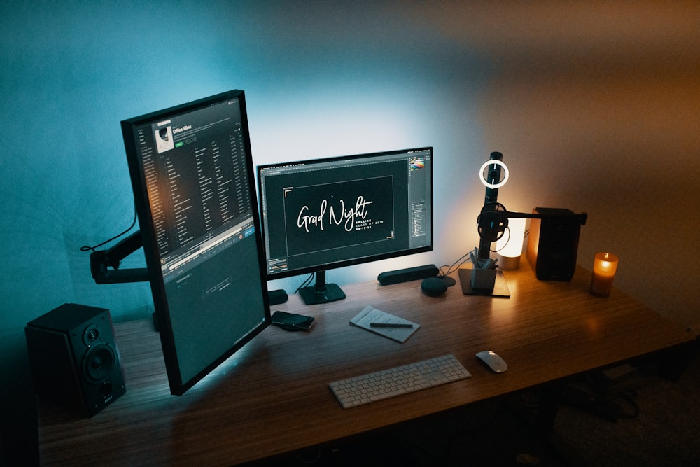 two turned-on flat screen monitors near Apple Magic Mouse and keyboard on table