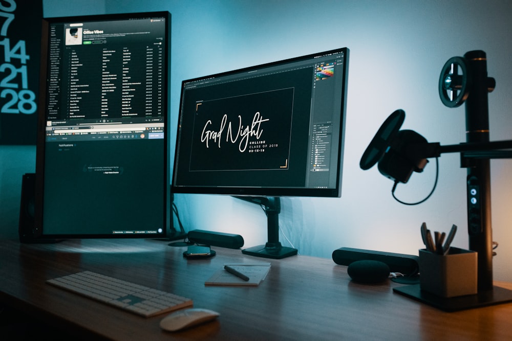 two flat screen computer monitors on table