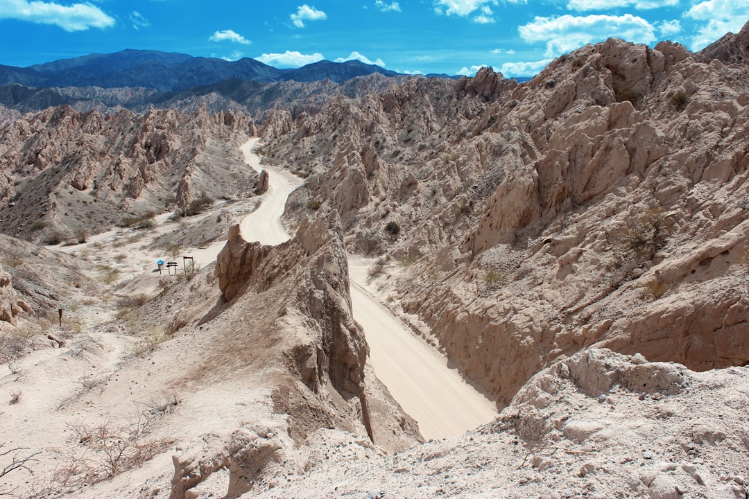 a group of people riding down a dirt road in the mountains,